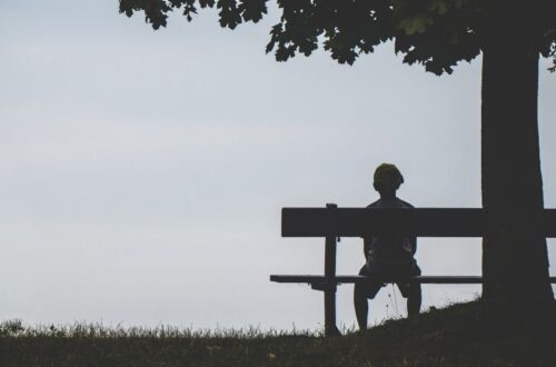 A person sitting in a bench feeling lonely looking for ways on how to overcome this feeling