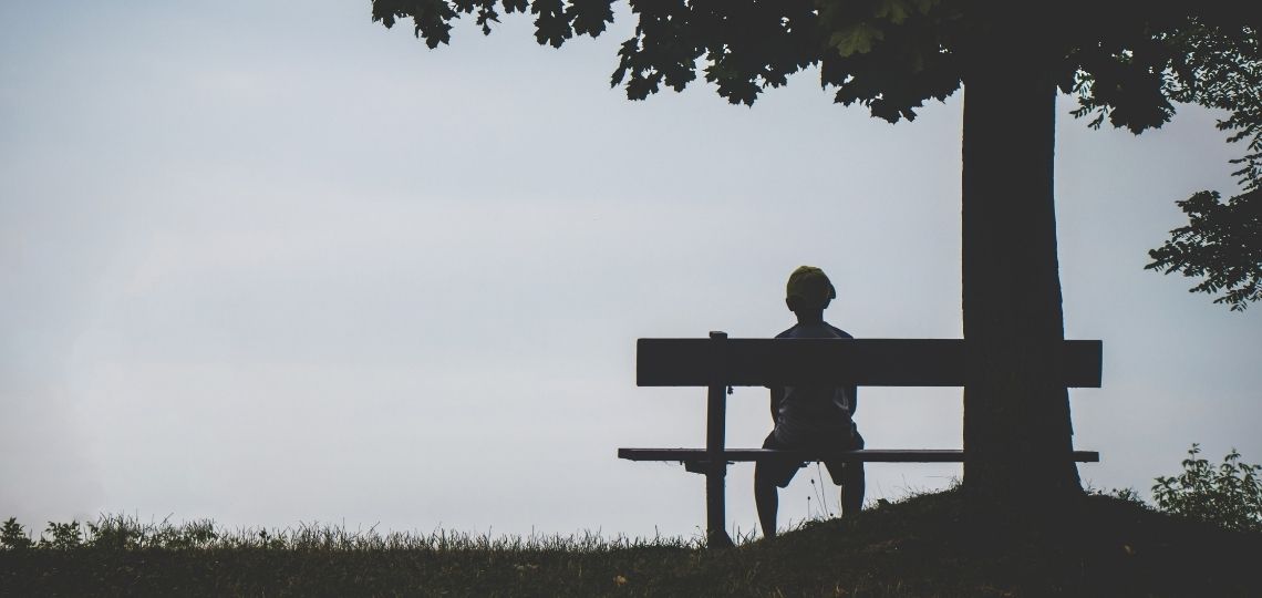 A person sitting in a bench feeling lonely looking for ways on how to overcome this feeling