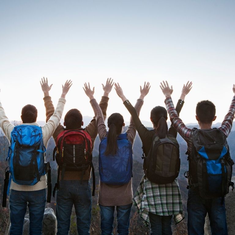 Friends posing on the top of mountain, enjoying growing together