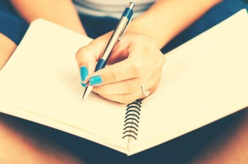 A woman writing plans on her journal, which is one the things to do on Sundays to have a productive week