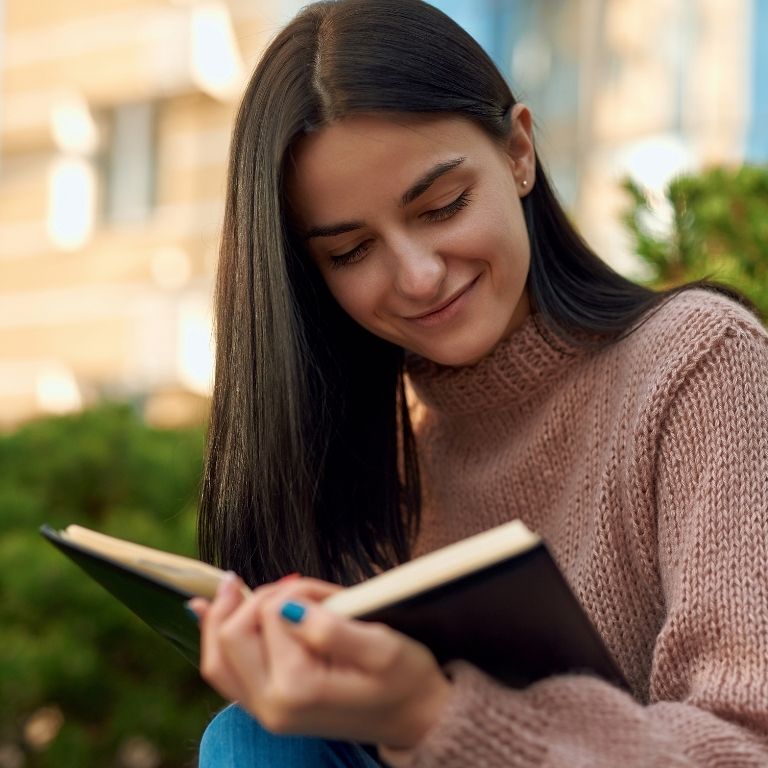 A woman using the journal prompts for the end of the year review, and she looks happy.