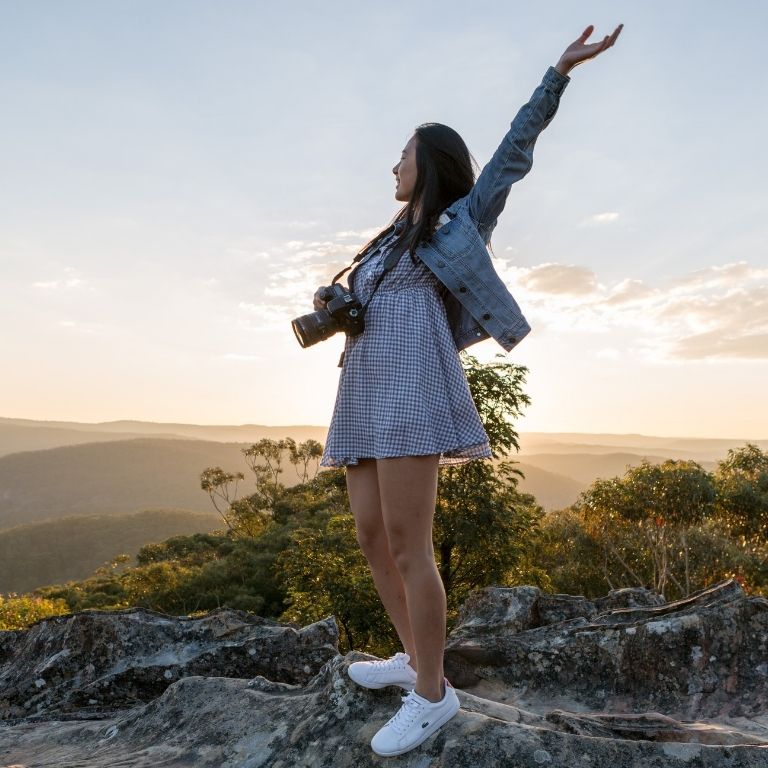 A woman who climbed a mountain. Poses with the sunset. She keep improving herself so she is happy