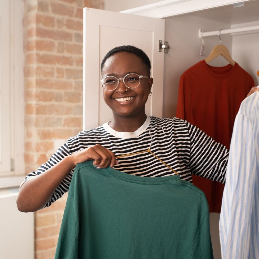 Woman smiling while organizing her closet.