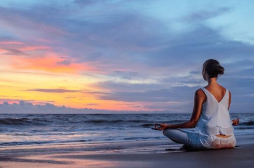 A woman meditating in the beach with a great sunset